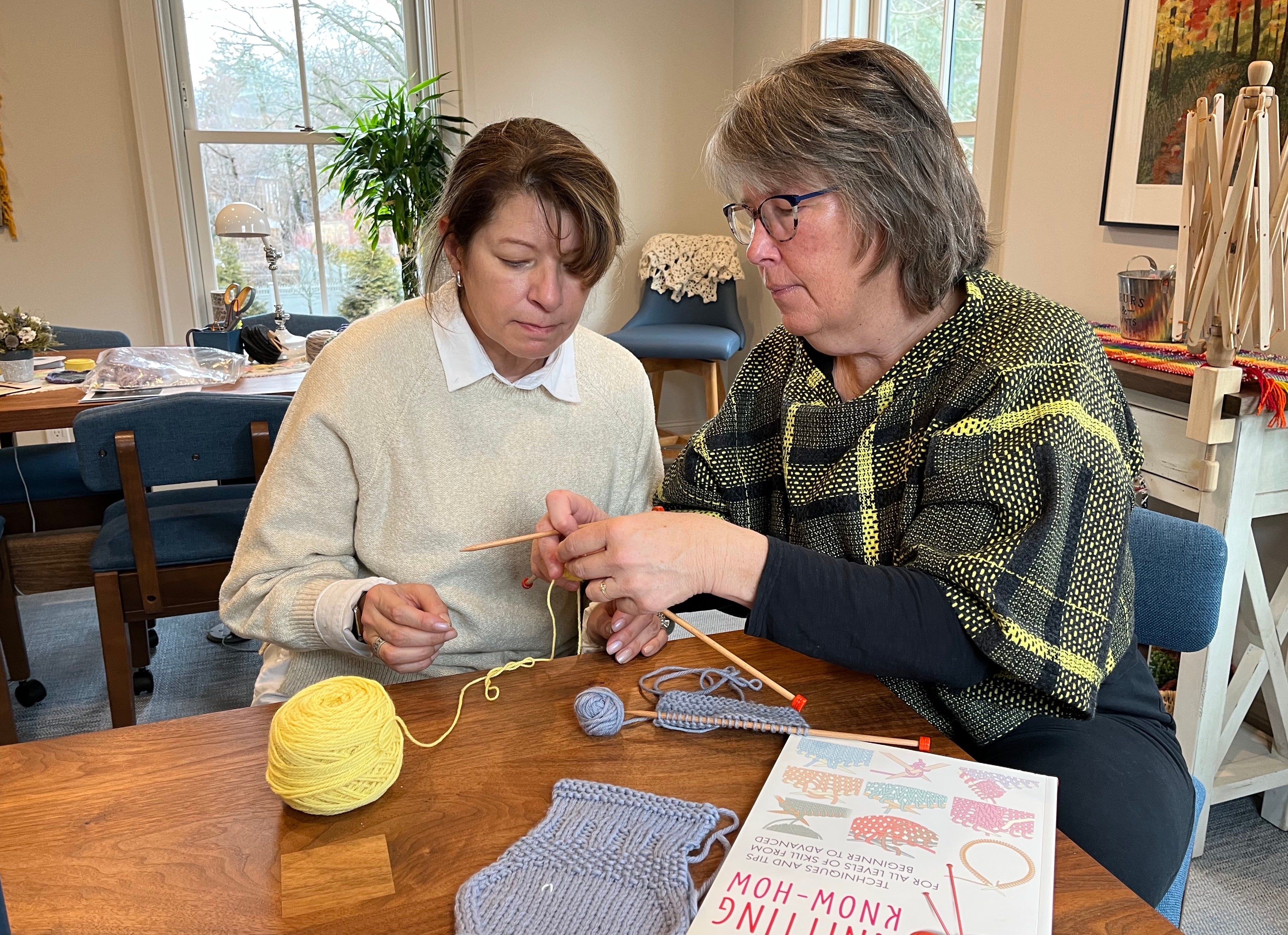A student working with a knitting teacher